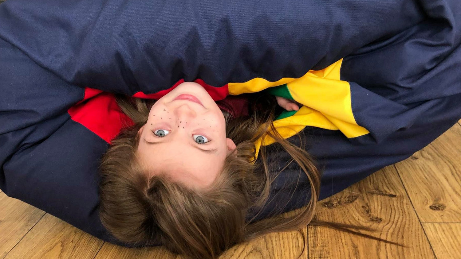 girl's head sticking out from the large sensory tunnel pouf